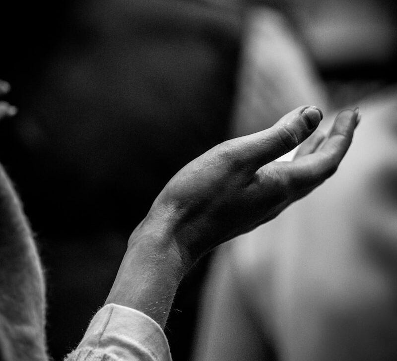A black and white photo of a person holding their hands together